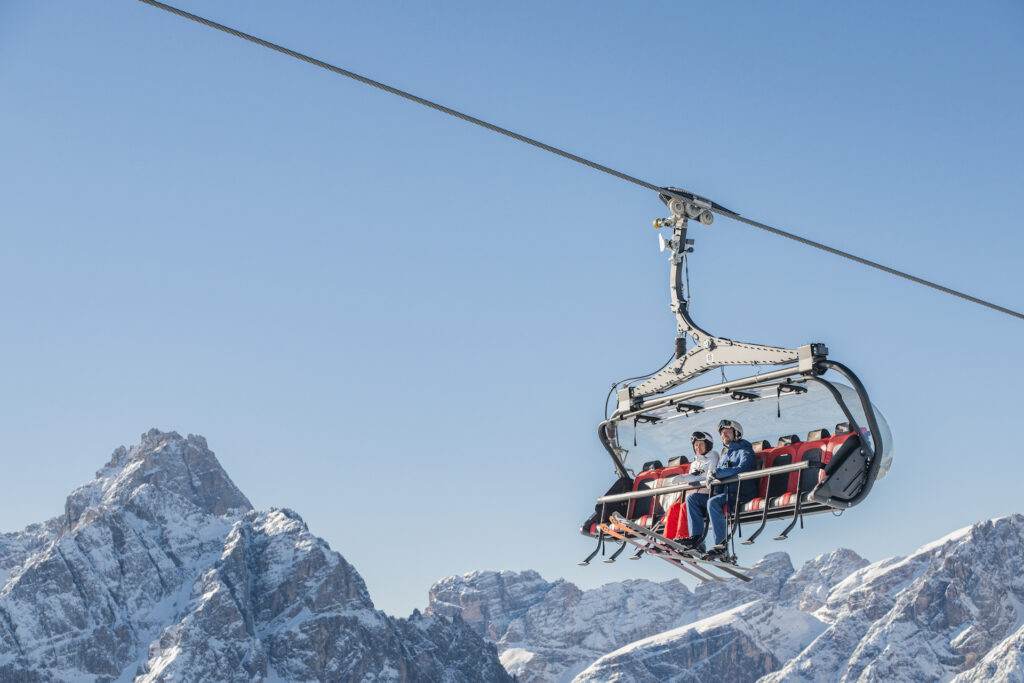 Пара на подъемник в 3 Zinnen Dolomites с горой позади них