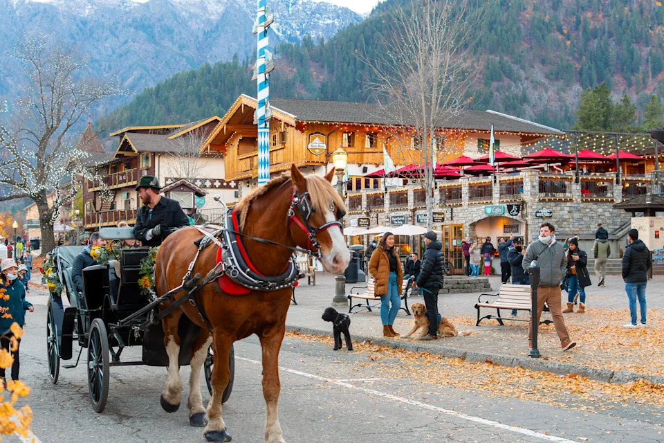 Повозка с лошадьми и водителем по главной улице живописной баварской тематической деревни Ливенворт Вашингтон в Каскадных горах в начале зимы.