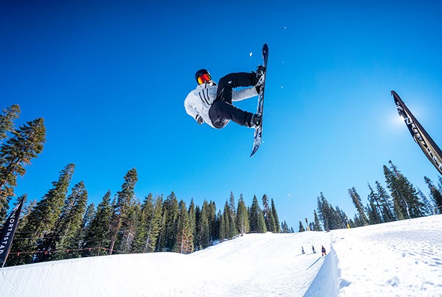 Сноубордист Northstar California прыгает в гибкой воздушной трубке.