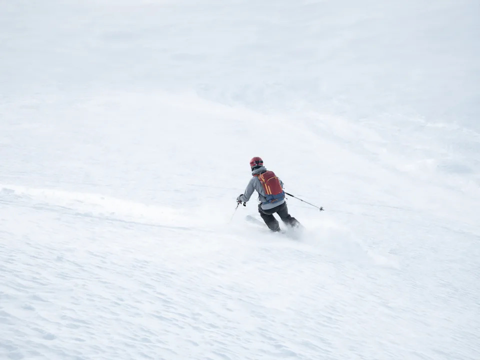 Одинокая лыжница прокладывает новую трассу на склоне горы во французских Альпах.