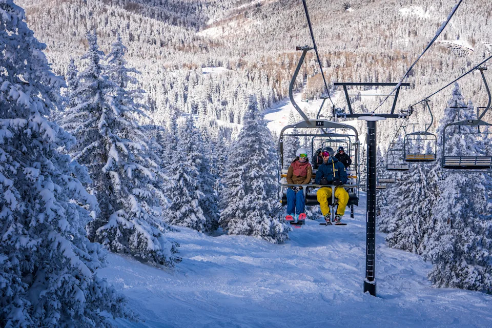 Три человека на подъемнике с деревьями и землей, покрытыми снегом