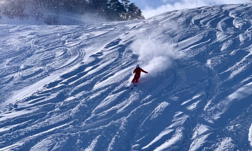 Лыжник в Ямагате Акакура-Онсэн на коротких лыжах под подъемником устраивает настоящее шоу. Изображение: Элиот Кокрейн