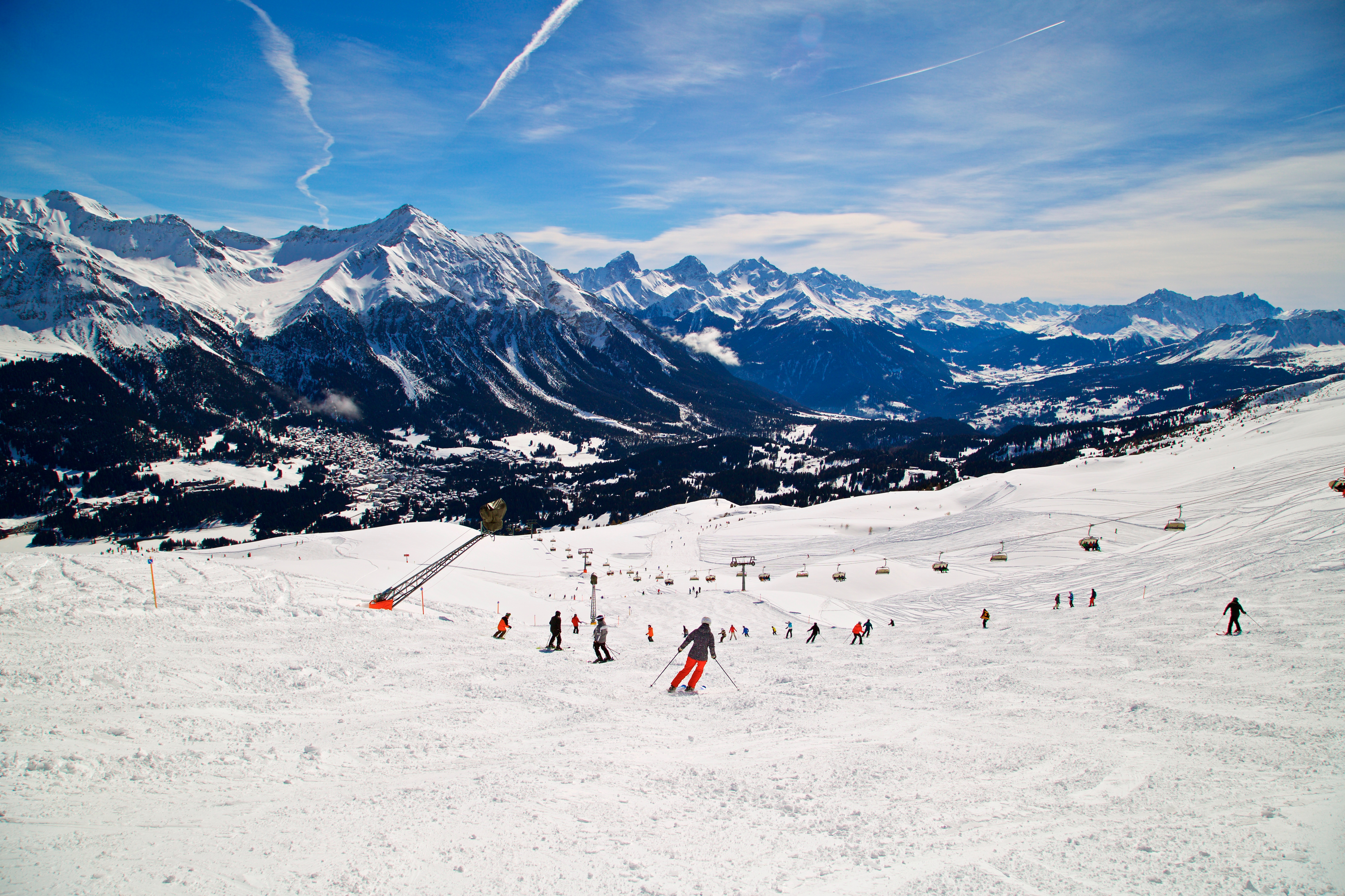 Зимнее катание на лыжах в Ленцерхайде, Граубюнден, Швейцария, с заснеженными горами, горнолыжными склонами, лыжниками и кресельными подъемниками.