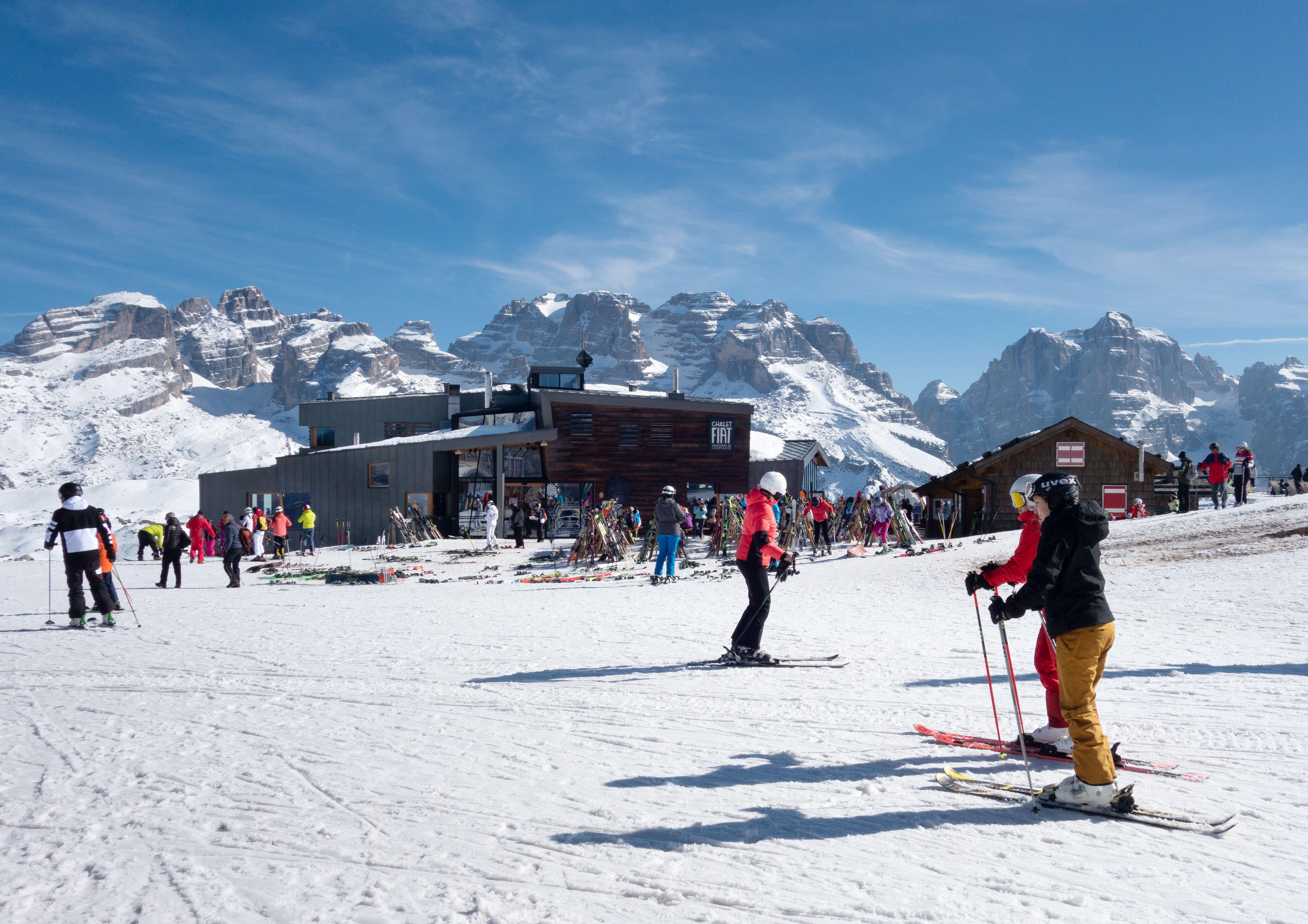 Лыжники приближаются к ресторану Chalet Fiat на горнолыжных склонах, Мадонна-ду-Кампильо, Доломитовые Альпы, Италия.