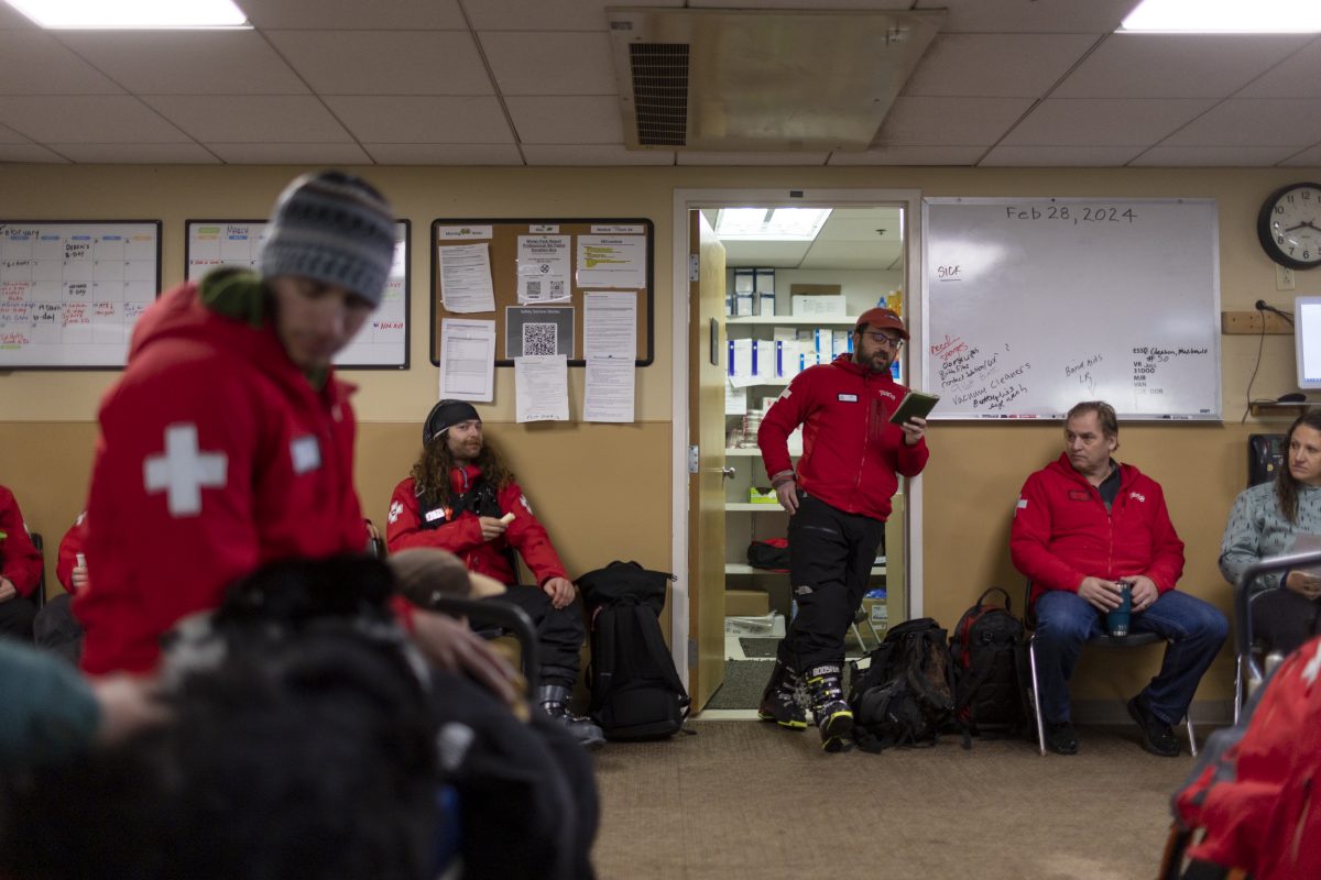 люди в красных верхних слоях стоят и сидят в комнате